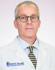 Man wearing a white doctor's coat and glasses.