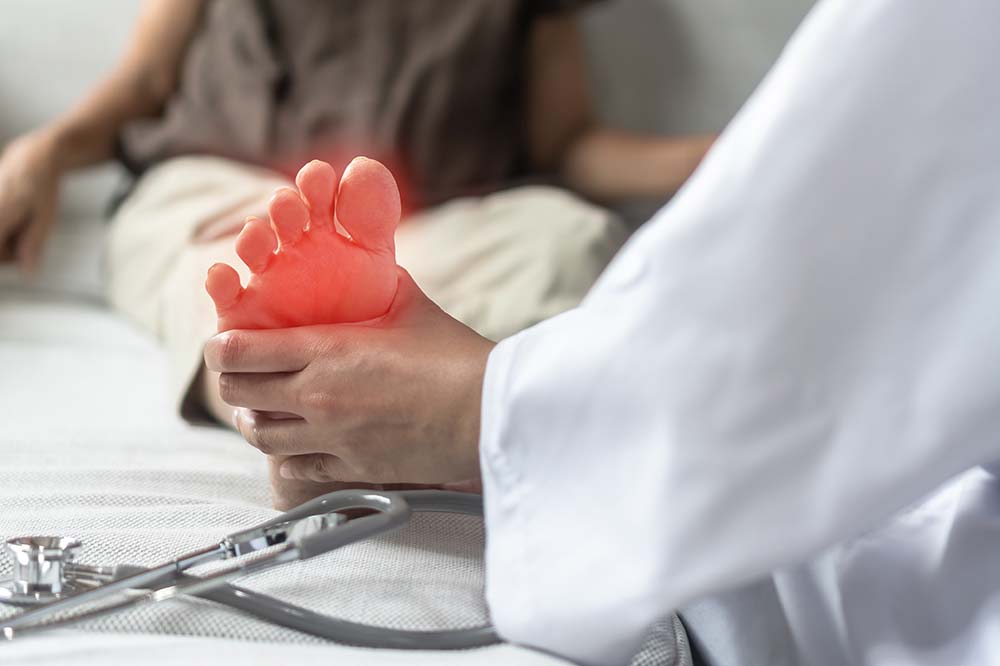A foot highlighted in red being touched by a person wearing a white coat.