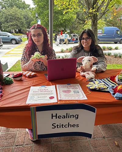 Two medical students at a table that says healing stitches.