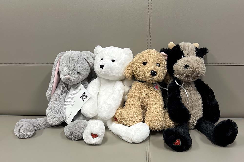 Four stuffed animals on a taupe colored seat. There is a bunny, a bear, a dog and a cow.