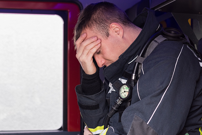 Firefighter sitting on fire truck tired and sad